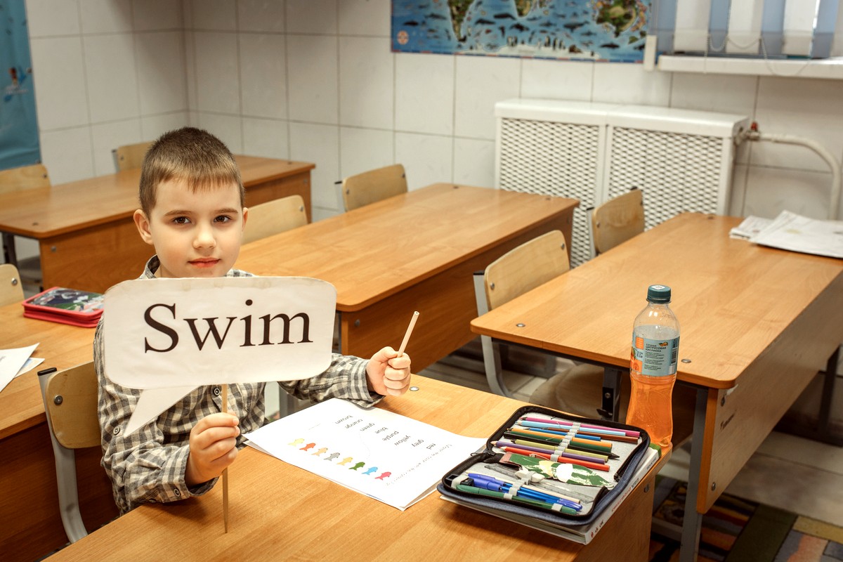 Мальчик показывает карточку Swim на занятии английским